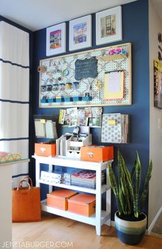 a desk with some pictures on the wall and a potted plant next to it