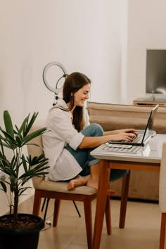 a woman sitting at a table using a laptop computer