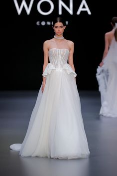 a woman in a white dress walking down the runway