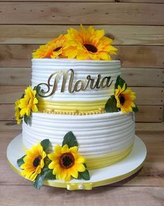 a three tiered cake with sunflowers on the top and name written on it