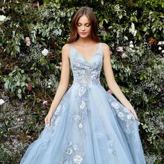 a woman in a blue dress standing next to flowers