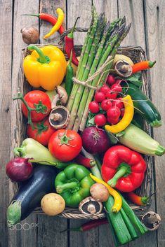 a crate filled with lots of different types of vegetables on top of a wooden table