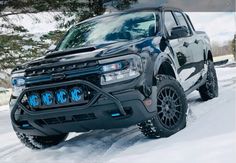 a black truck driving down a snow covered road