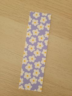 a piece of paper with yellow dots and white flowers on it sitting on a wooden table