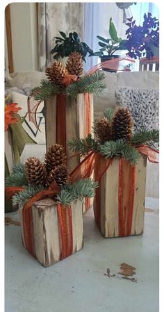 three wooden blocks with pine cones and ribbons tied around them, sitting on a table