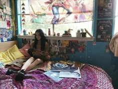 a young woman sitting on top of a bed next to a window with comic books