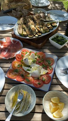 an assortment of food sitting on top of a wooden table next to plates and utensils