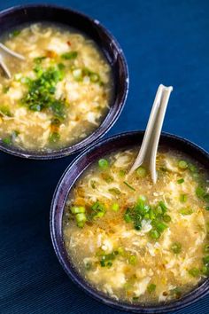 two bowls of soup with chopsticks in them on a blue tablecloth,