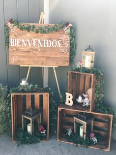 three wooden crates with flowers and candles on them sitting in front of a sign that says benvendos