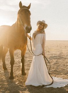 a woman standing next to a horse in the desert