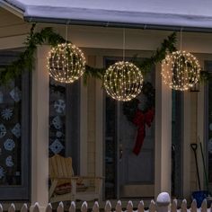 christmas lights hang from the front porch of a house decorated with wreaths and garland