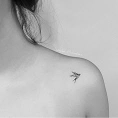 a black and white photo of a woman's shoulder with a small bird on it