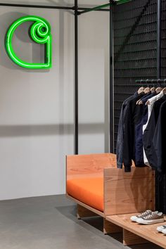 a clothing store with clothes hanging on racks and an orange bench in the foreground