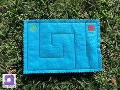 a blue piece of cloth laying on top of green grass with a square shaped design