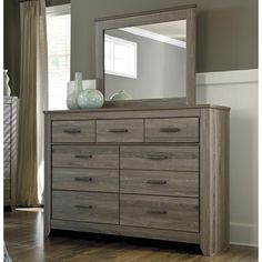 a dresser with a mirror and vases on it