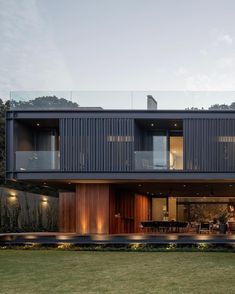 a modern house with large windows and wooden sidings on the outside, along with an outdoor dining area