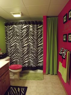 a bathroom with zebra print shower curtain and pink accent wall, white toilet and black and green curtains