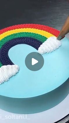 someone is decorating a rainbow cake with white icing