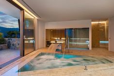 an indoor hot tub with water running down the side and sliding glass doors leading outside