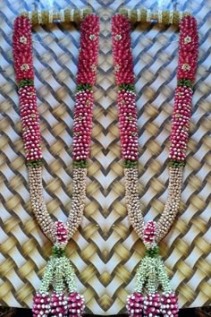 two red and white beaded necklaces are hanging on a wall next to each other