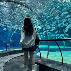 a woman standing in front of an aquarium looking at fish