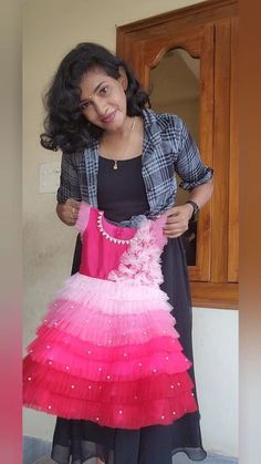 a woman in a pink and black dress is holding up a piece of clothing that has been made from tulle