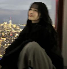 a woman sitting on top of a building looking out at the city from her window