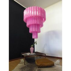 a pink chandelier hanging from the ceiling in a room with a rug on the floor