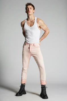 a man in white tank top and pink pants standing with his hands on his hips