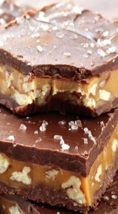 three chocolate bars stacked on top of each other with nuts and sea salt all over them