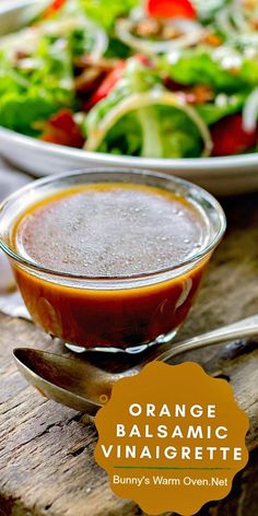 an orange balsamic vinaigrette in a bowl next to a salad