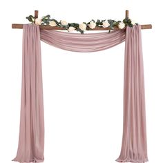 a wooden cross decorated with flowers and greenery on top of a pink drape