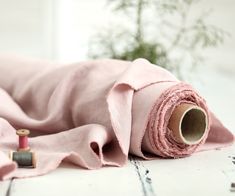 a roll of pink fabric next to a spool of thread