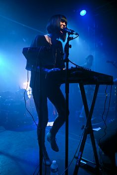 a woman standing on top of a keyboard in front of a microphone at a concert