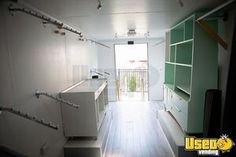 an empty kitchen with white cabinets and green shelves on the wall next to a door