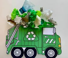 a green garbage truck with flowers and plastic bottles in it's back end, on a white background