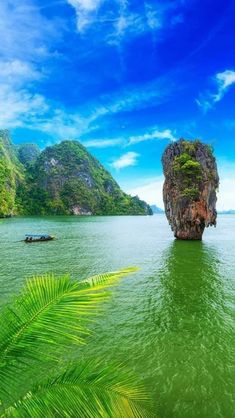 an island in the middle of water surrounded by mountains and palm trees on either side