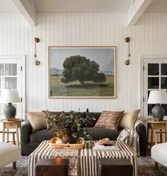 a living room filled with furniture and a painting hanging on the wall above it's coffee table