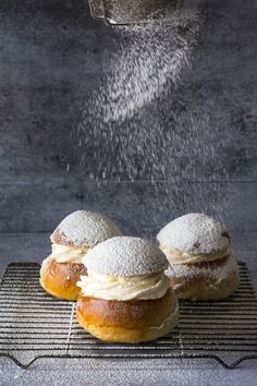 powdered sugar sprinkled over three donuts on top of a cooling rack