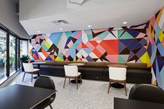 a room with tables, chairs and colorful wallpaper on the walls in it's center