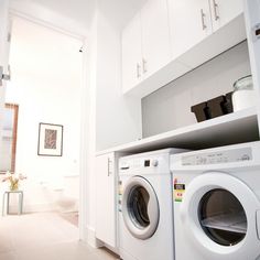 there is a washer and dryer in this small laundry room with white cabinets