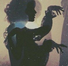 the silhouette of a woman holding a bird in front of her face and hands behind her back