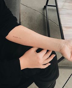 a woman's arm with the word love tattooed on it, sitting at a table