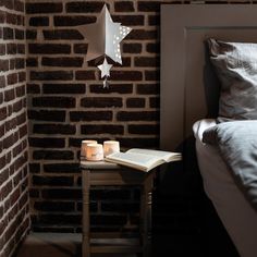 a bedroom with brick walls and a small table next to the bed that has two candles on it