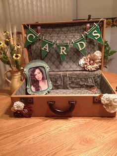 an open suitcase sitting on top of a wooden table next to flowers and bunting