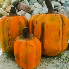 three orange pumpkins sitting next to each other on top of a pile of rocks