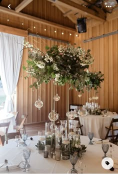 an elegant centerpiece with greenery sits on a table in the middle of a banquet hall