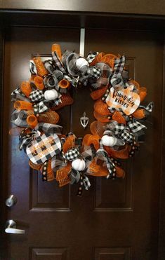 an orange and black wreath on a door with the words happy halloween written on it