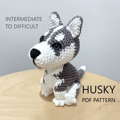 a crocheted dog sitting on top of a wooden table next to a gray and white stuffed animal