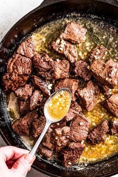 a skillet filled with steak and mustard being stirred by a spoon to stir it